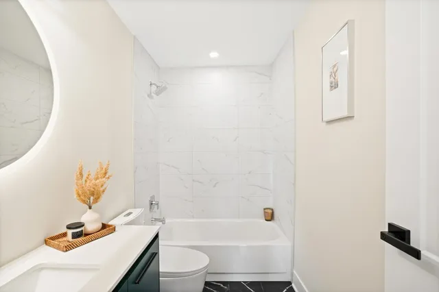 a bathroom with a bathtub sink mirror vanity and toilet
