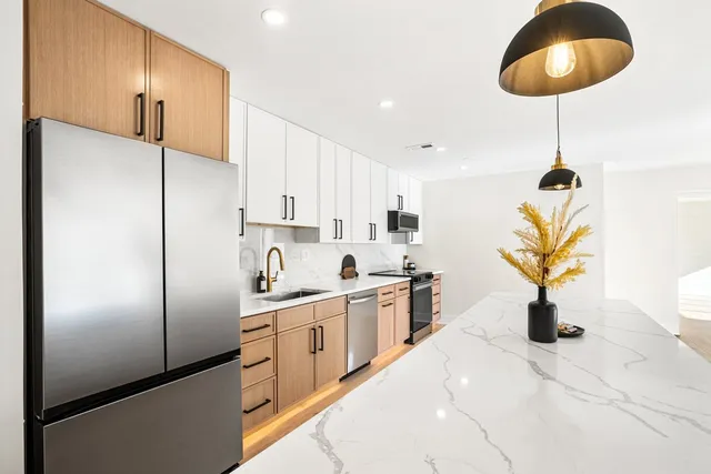 a kitchen with stainless steel appliances kitchen island granite countertop a refrigerator a sink a stove and a wooden floors