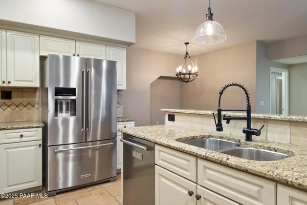 a kitchen with stainless steel appliances granite countertop a refrigerator a sink a stove and a refrigerator