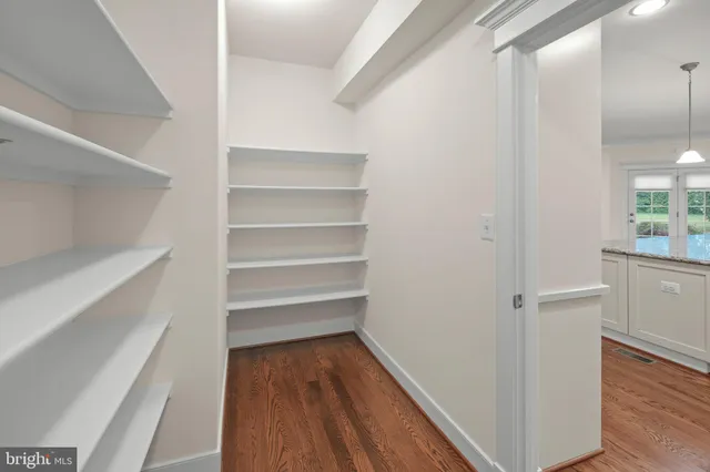 an empty room with wooden floor ceiling fan and windows