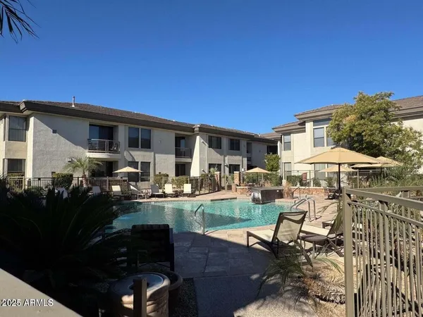 a view of a patio with table and chairs under an umbrella with a barbeque grill