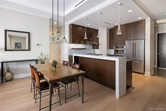 a kitchen with stainless steel appliances a dining table chairs microwave and refrigerator