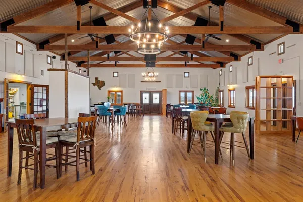 a dining room with lots of wooden furniture a chandelier and wooden floor