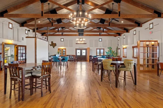 a dining room with lots of wooden furniture a chandelier and wooden floor