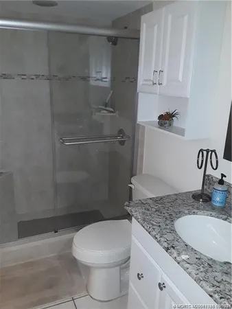 a bathroom with a granite countertop sink toilet and shower