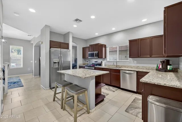 a kitchen with stainless steel appliances granite countertop a refrigerator a sink a stove a microwave and island