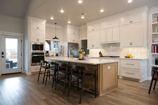a kitchen with white cabinets stainless steel appliances and dining table