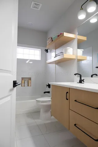 a bathroom with a sink a toilet a shower and a window