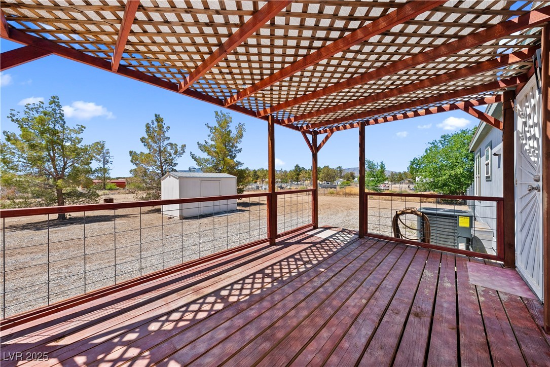 1391 East Casey Road Pahrump, NV 89048 - Photo 29 of 40 Wooden deck with a storage shed, a pergola, an outbuilding, and central AC unit