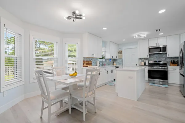 a kitchen with microwave a stove a dining table and chairs