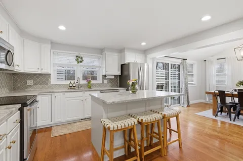 a kitchen with kitchen island granite countertop wooden floors and white cabinets