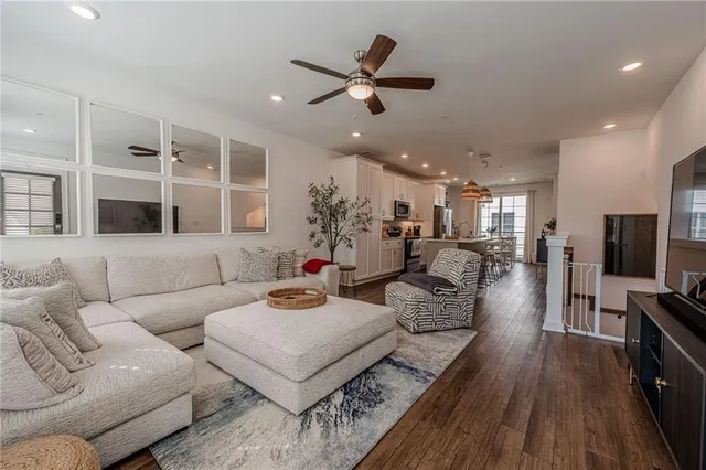 a living room with furniture kitchen view and a wooden floor
