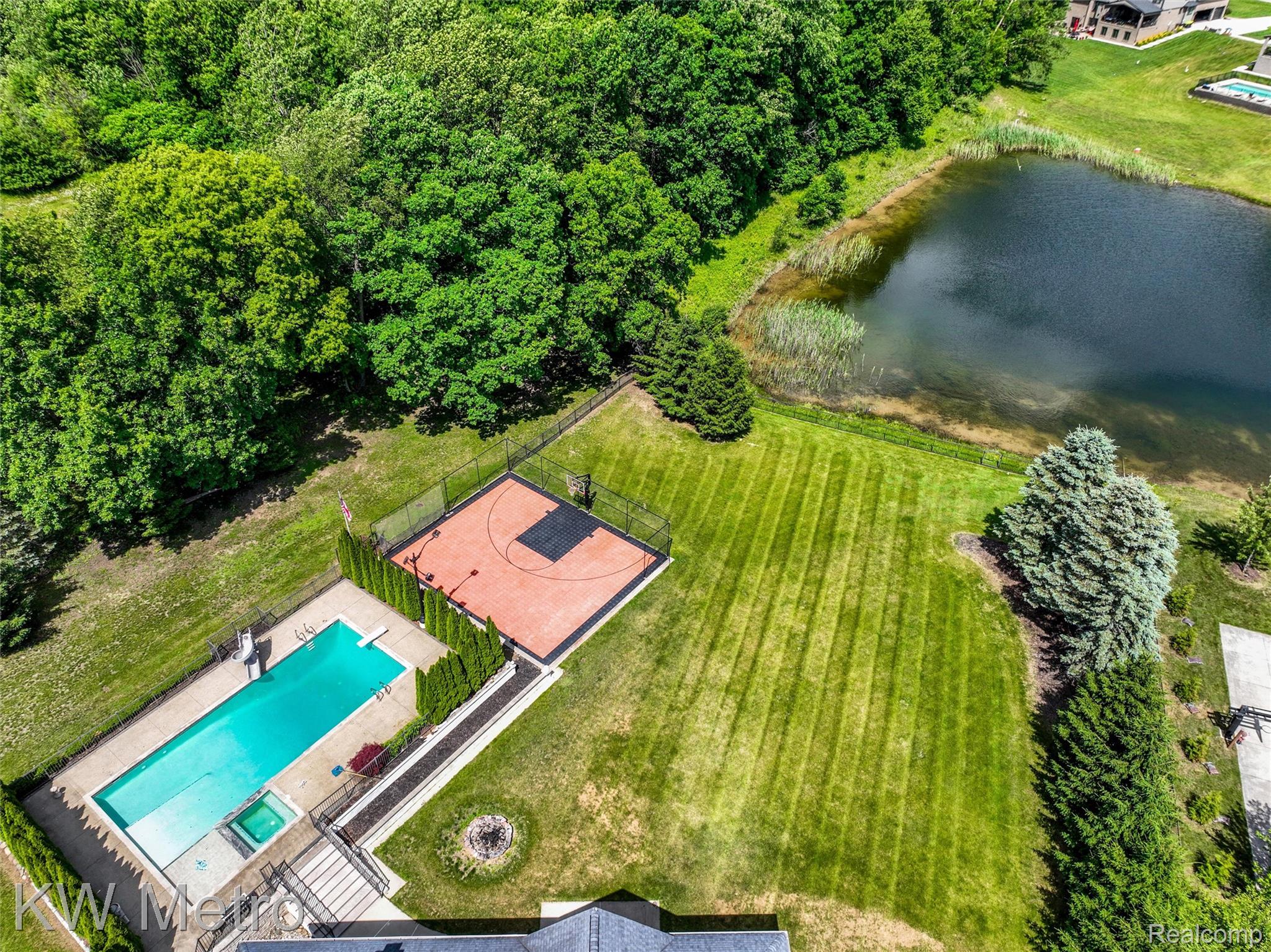 65884 Windrose Court Ray, MI 48096 - Photo 20 of 82 Expansive rear grounds with a rectangular swimming pool, integrated spa, and adjacent hard-surface sports court