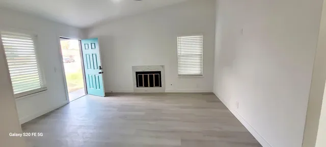 an empty room with windows and fireplace