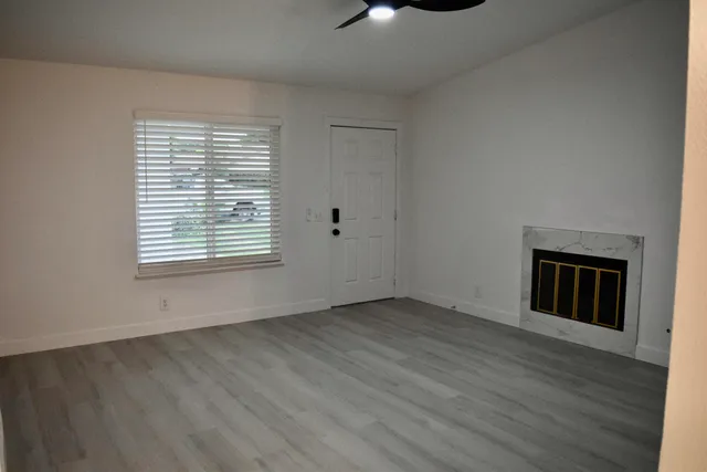 an empty room with wooden floor cabinet and windows