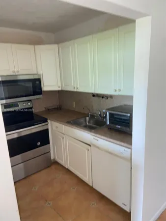 a kitchen with granite countertop white cabinets and stainless steel appliances