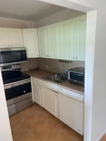 a kitchen with granite countertop white cabinets and stainless steel appliances