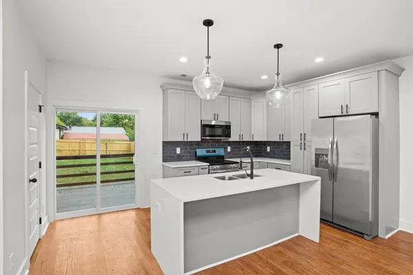 a kitchen with kitchen island a sink stainless steel appliances and white cabinets