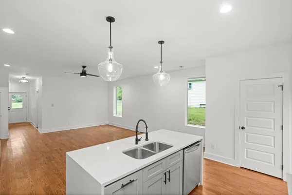 a kitchen with kitchen island a sink stainless steel appliances and wooden floor