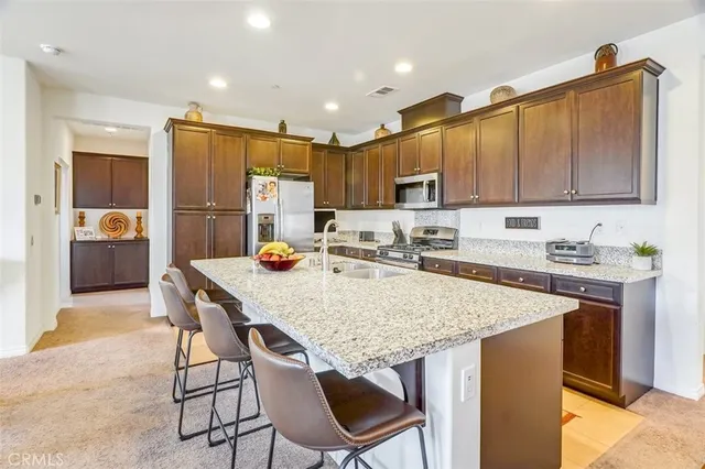 a kitchen with stainless steel appliances granite countertop a table chairs sink refrigerator and cabinets