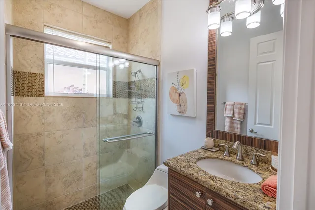 a bathroom with a granite countertop sink mirror vanity and toilet