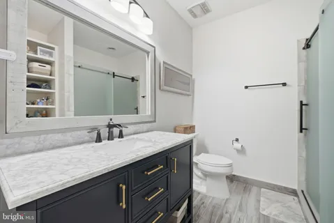 a bathroom with a granite countertop sink a toilet and a mirror