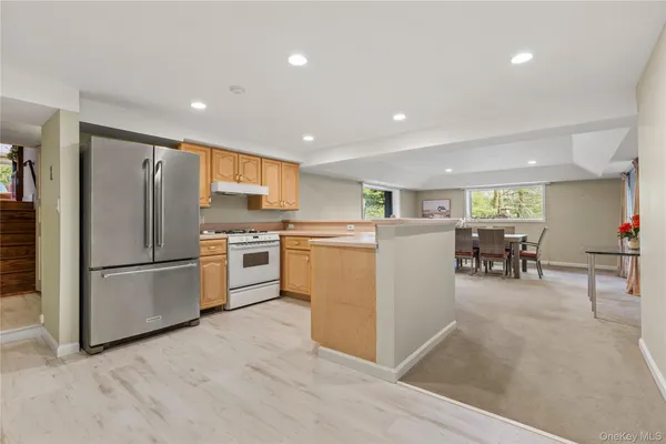 a kitchen with a refrigerator a stove top oven a sink a dining table and chairs