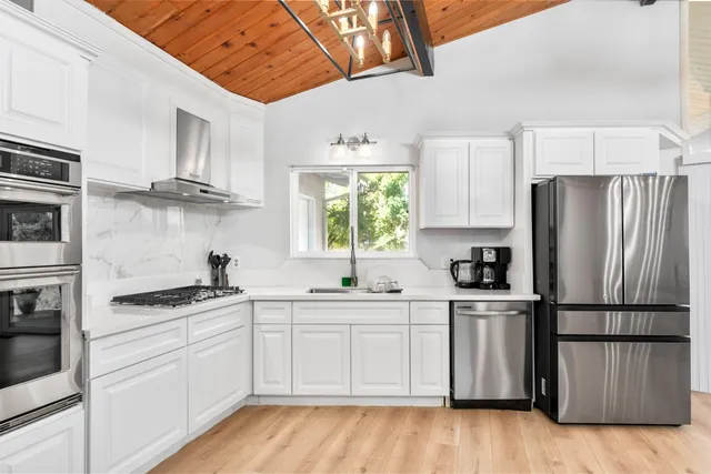 a kitchen with white cabinets sink and appliances