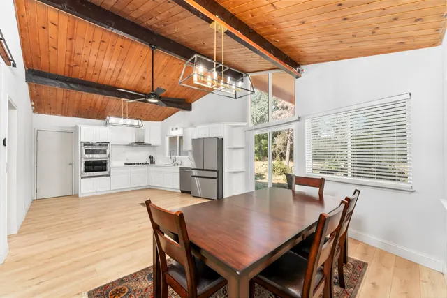 a dining room with stainless steel appliances granite countertop a kitchen island a table and chairs with wooden floor
