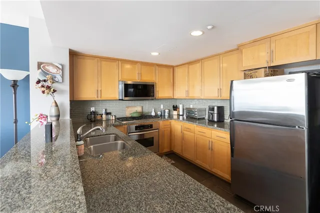 a kitchen that has a refrigerator a stove a sink a dining table and chairs