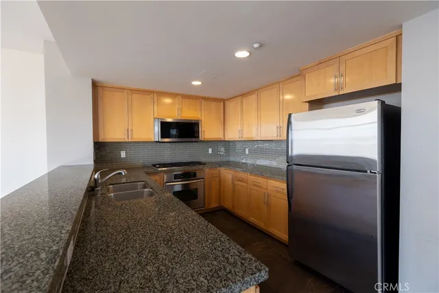 a kitchen with granite countertop a refrigerator and a sink
