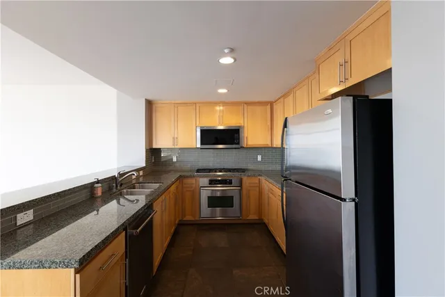a kitchen with granite countertop a refrigerator stove and oven