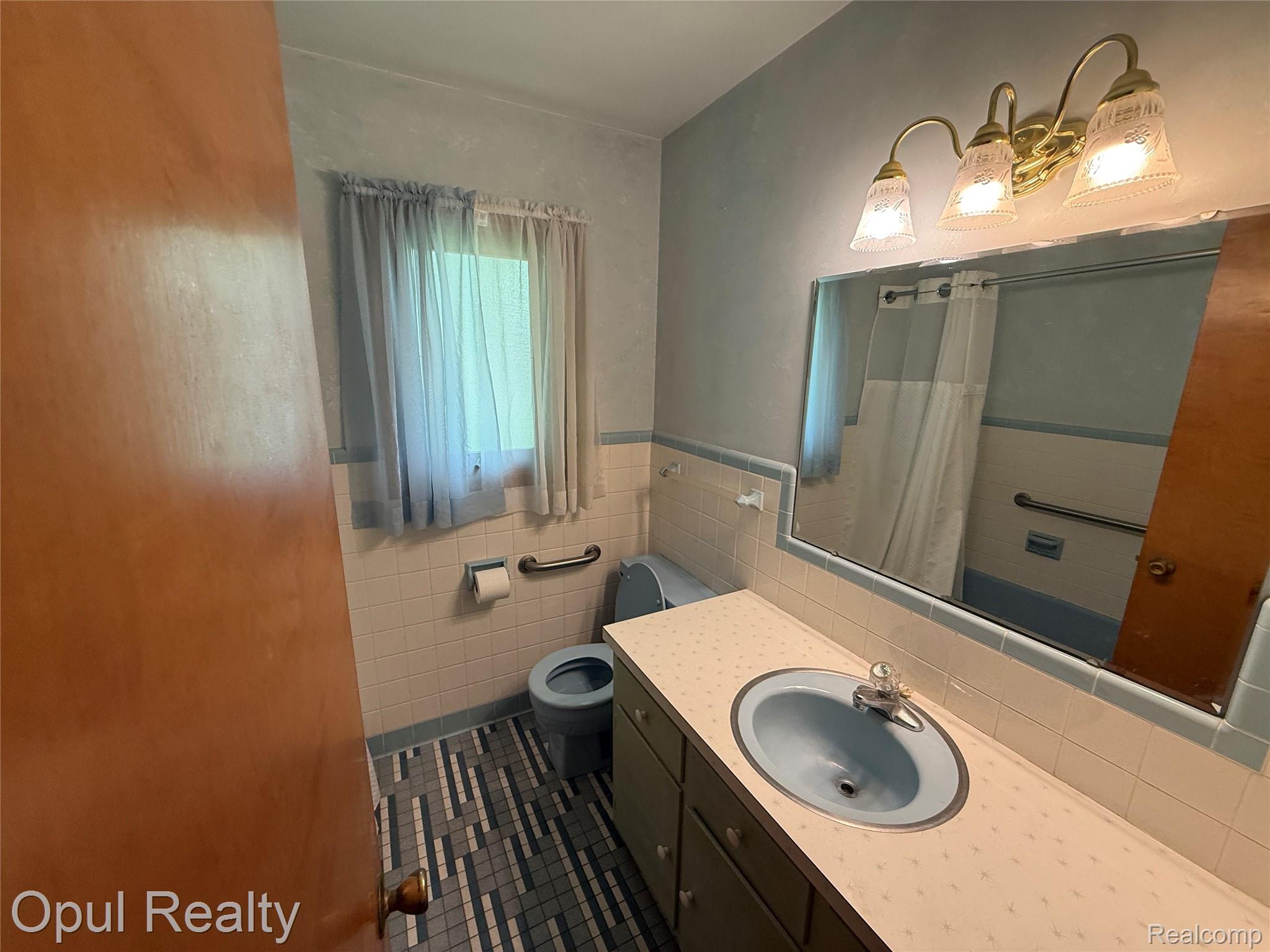 7899 Ida East Road Ida, MI 48140 - Photo 29 of 48 Bathroom featuring a single vanity with an integrated basin, a wall-mounted mirror, and a three-light fixture