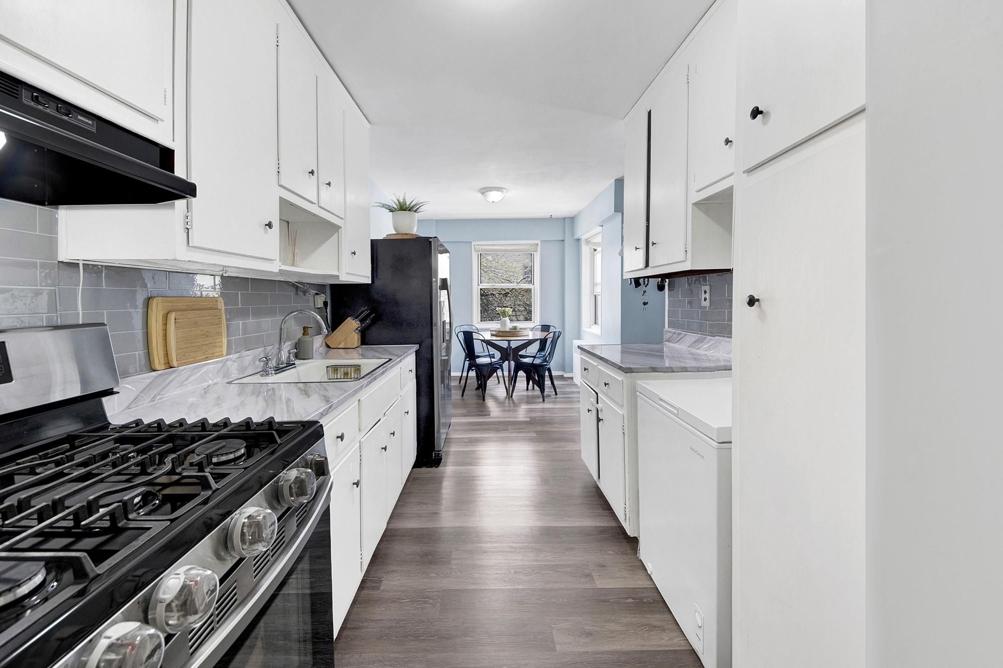 3130 Irwin Avenue, Unit 2C Bronx, NY 10463 - Photo 7 of 30 Kitchen with stainless steel appliances, a sink, wood finished floors, light countertops, and under cabinet range hood