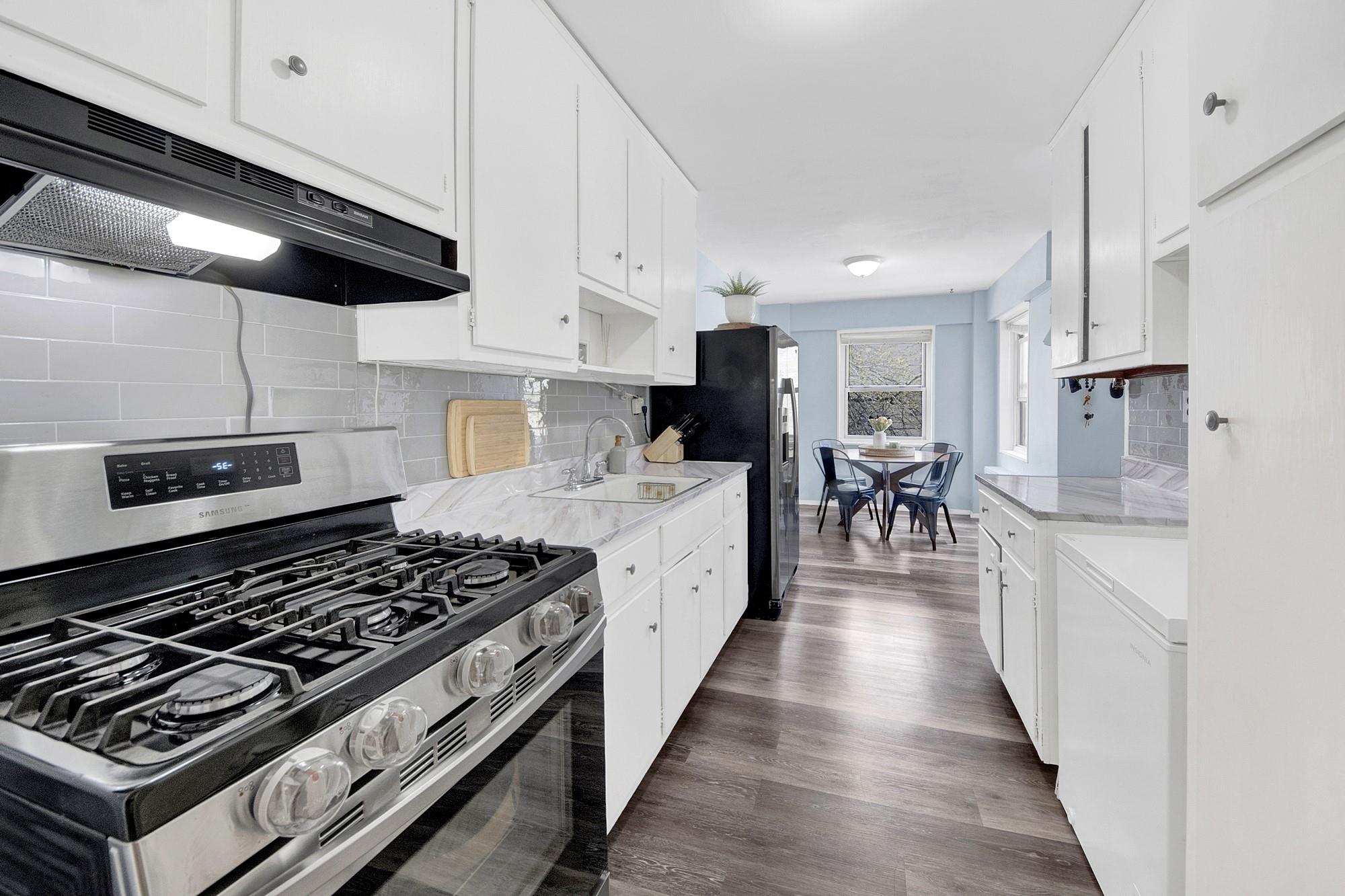3130 Irwin Avenue, Unit 2C Bronx, NY 10463 - Photo 9 of 30 Kitchen with under cabinet range hood, light countertops, backsplash, a sink, and appliances with stainless steel finishes