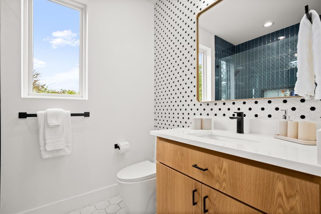 2919 East 13th Street, Unit 2 Austin, TX 78702 - Photo 13 of 20 a bathroom with a granite countertop sink a toilet a mirror a vanity and shower