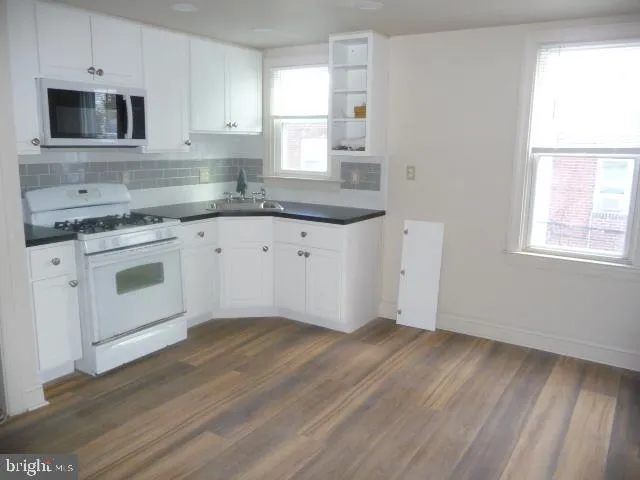 a kitchen with granite countertop white cabinets stainless steel appliances a sink and a window