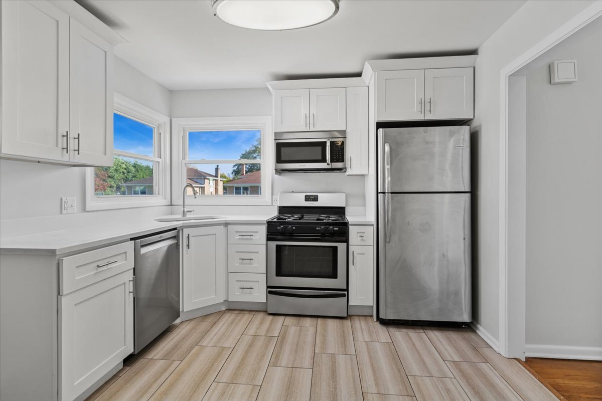 8846 North Ozanam Avenue Niles, IL 60714 - Photo 13 of 24 a kitchen with cabinets stainless steel appliances a sink and wooden floor