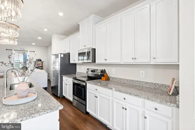 a kitchen with granite countertop white cabinets and stainless steel appliances