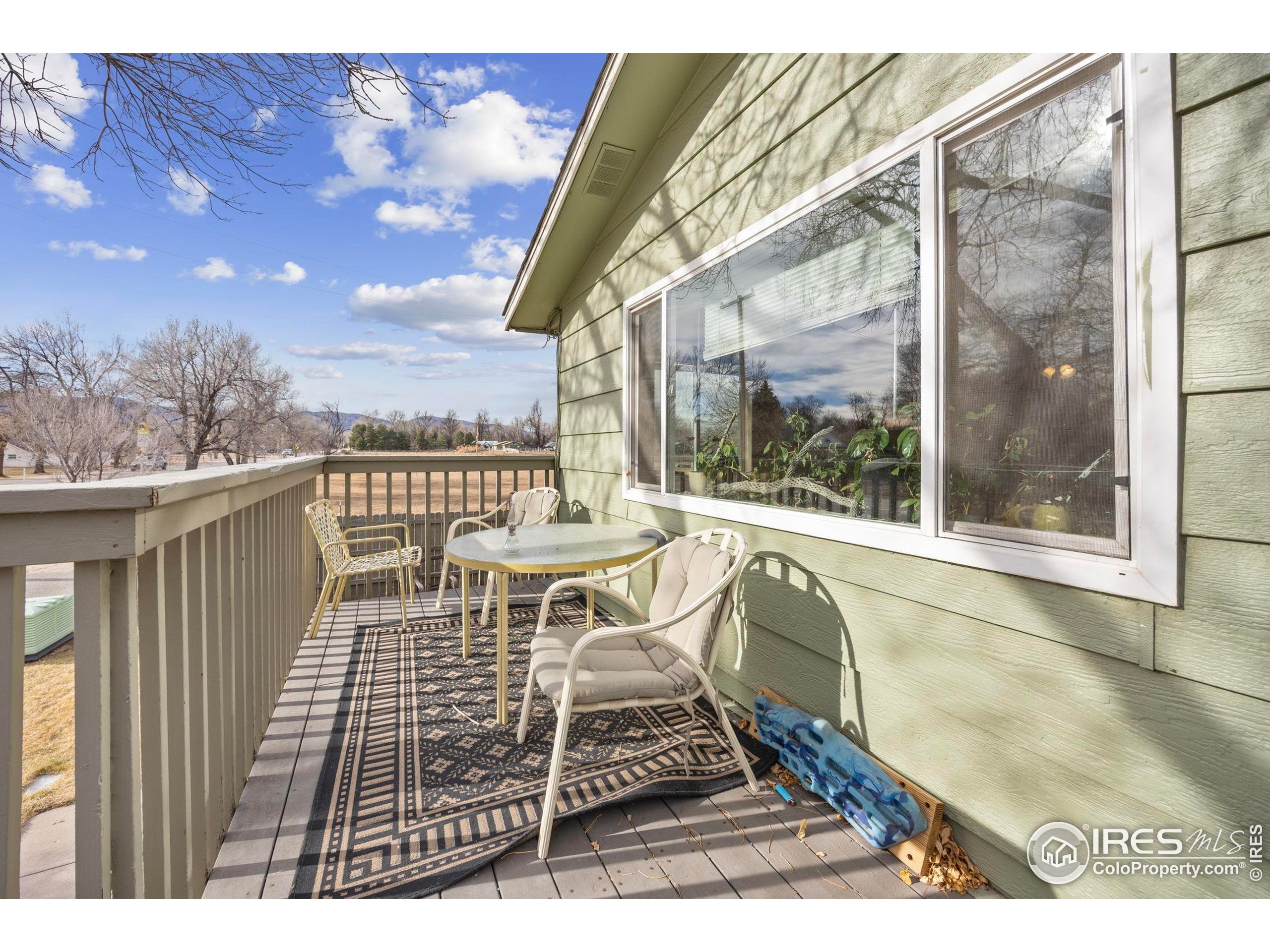 701 Aztec Drive Fort Collins, CO 80521 - Photo 16 of 43 a view of a roof deck with table and chairs with wooden floor and fence