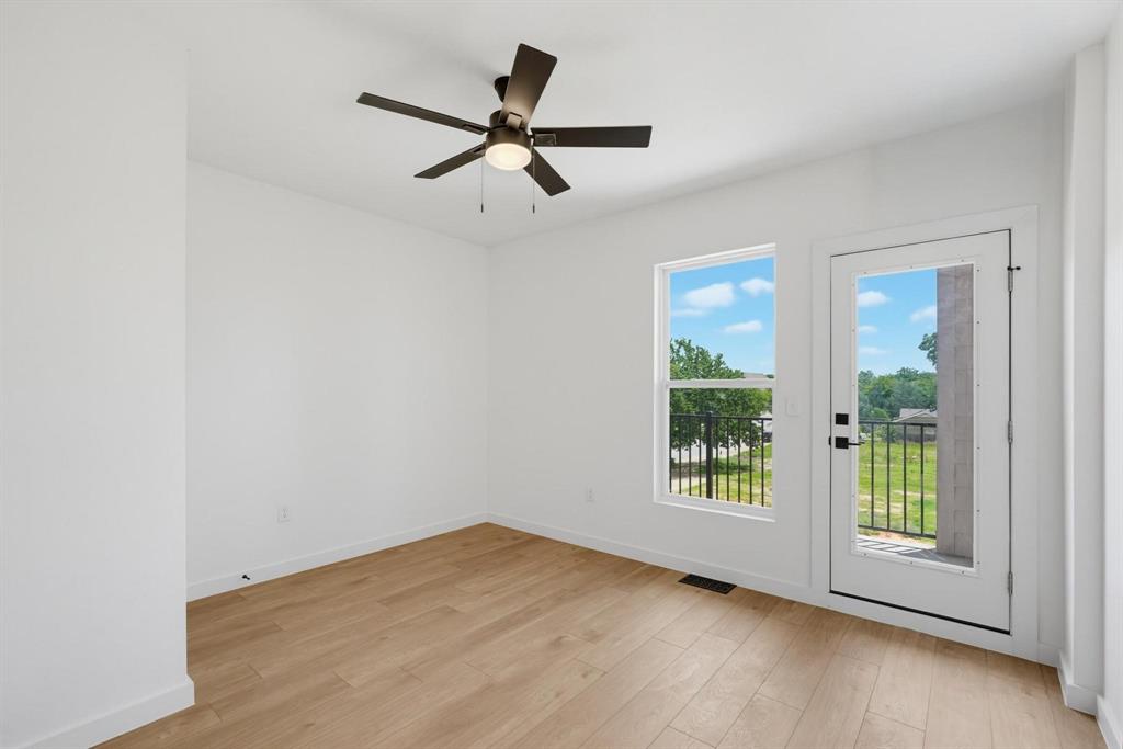 508 South O Connor Road Irving, TX 75060 - Photo 18 of 21 Spacious room featuring wood-finish flooring, a contemporary ceiling fan with integrated lighting, and a glass-paneled door opening to a balcony with black metal railing