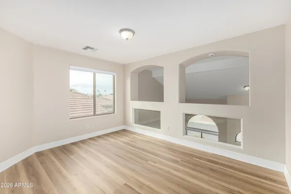 a view of an empty room with wooden floor and a window