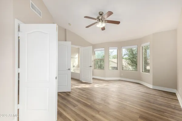 a view of an empty room with a window and wooden floor