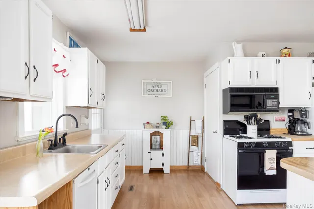 a kitchen with kitchen island wooden cabinets a sink a stove and wooden floor