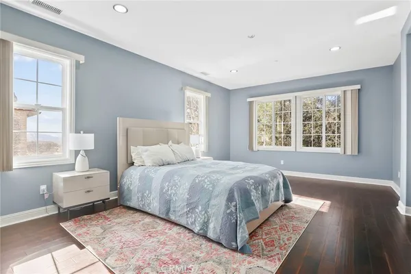 a bedroom with a large bed and wooden floor