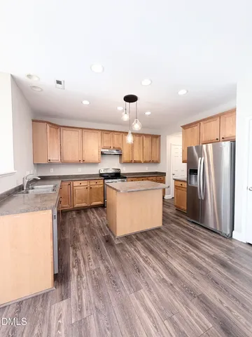 a large kitchen with a large counter top a sink stainless steel appliances and cabinets