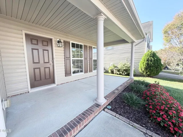 a view of yellow house with wooden walls and flower plants