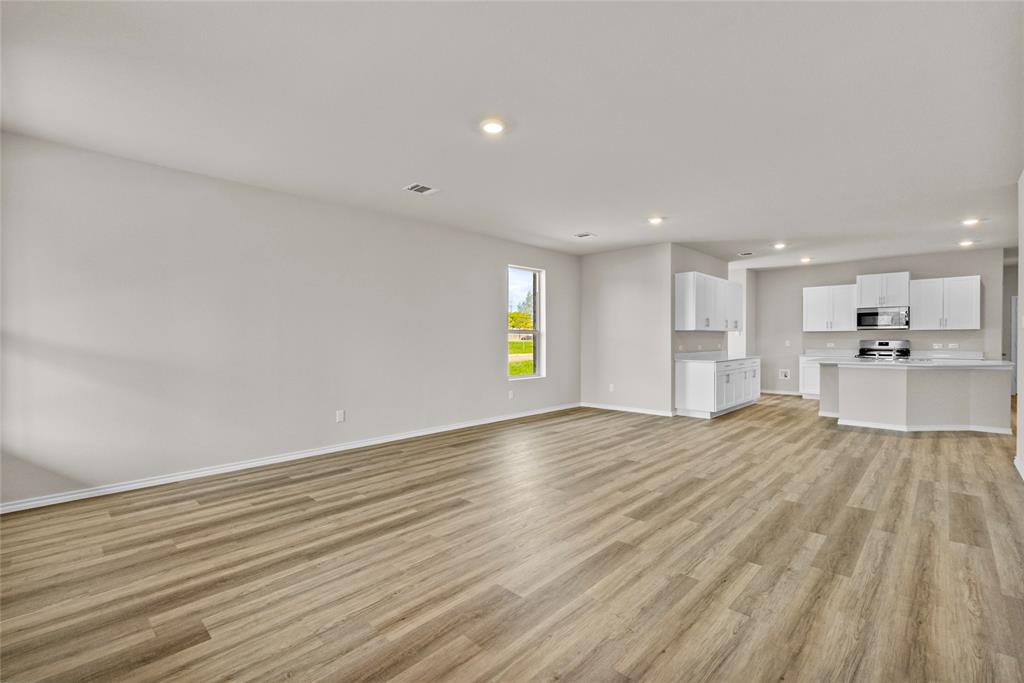 904 Traction Trail Cleburne, TX 76031 - Photo 7 of 27 a view of an empty room with wooden floor and a window