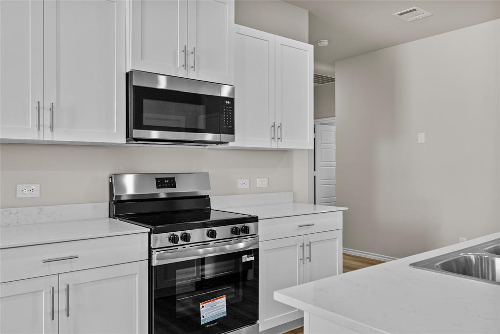 904 Traction Trail Cleburne, TX 76031 - Photo 10 of 27 a kitchen with white cabinets and black appliances