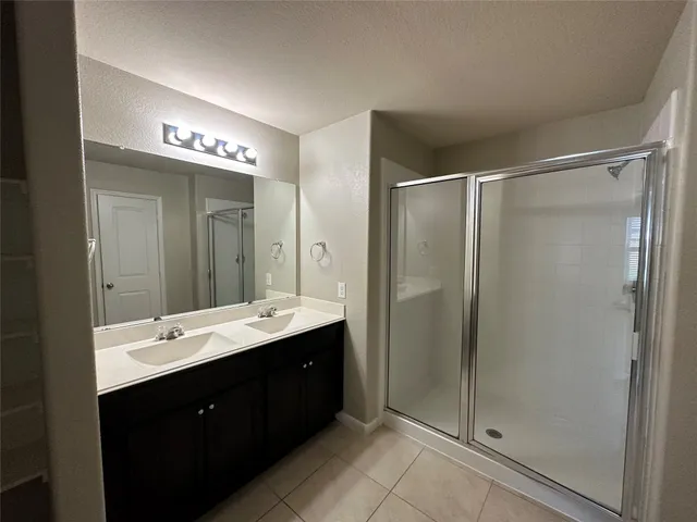 a bathroom with a double vanity sink mirror and shower
